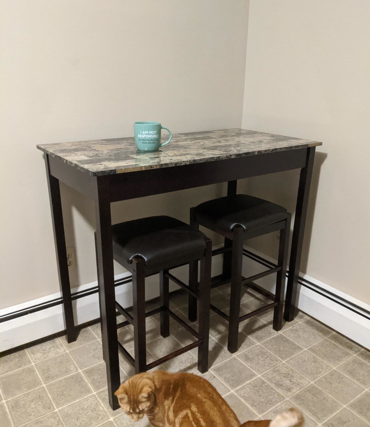 Reviewer pic of the tall table in brown with a marble-like top and two stools under it, also in brown