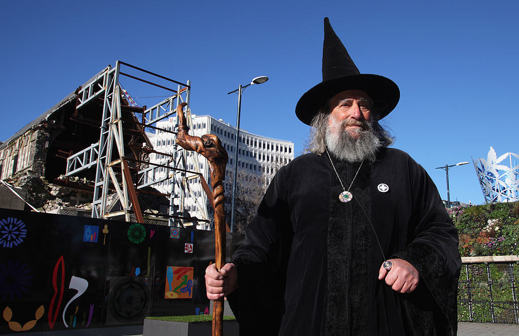 Ian Brackenbury Channell wearing wizard robes and a pointy hat, and holding a wooden staff