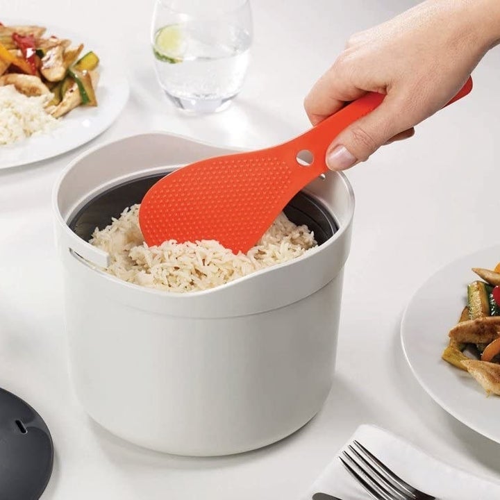 A person about to scoop rice out of the cooker