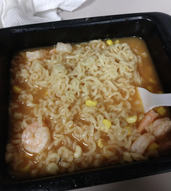 A reviewer photo of their ramen inside the cooker with shrimp and corn