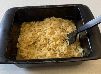 A reviewer photo of a fork digging into the ramen inside of the cooker