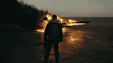 Farrier standing in front of a plane on fire.