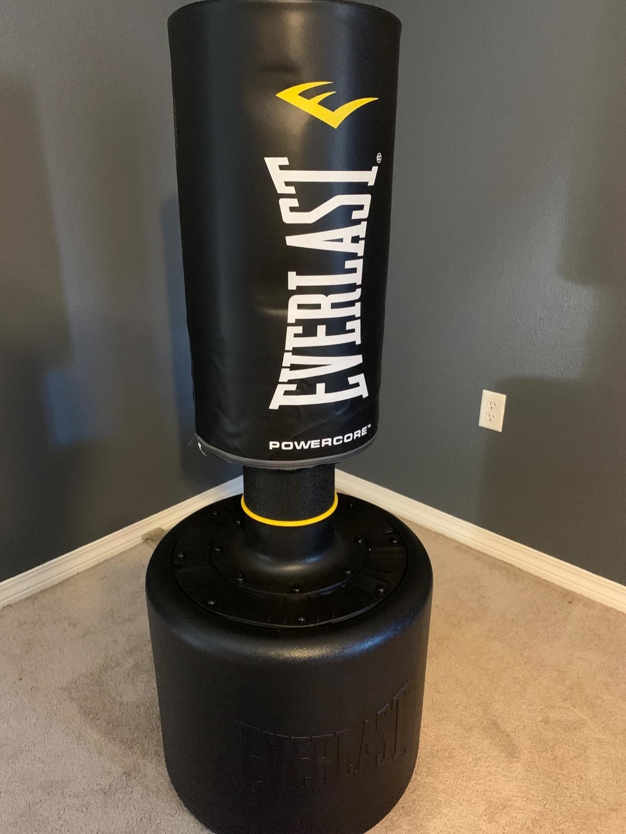 A reviewer showing the adjustable punching bag on a stand