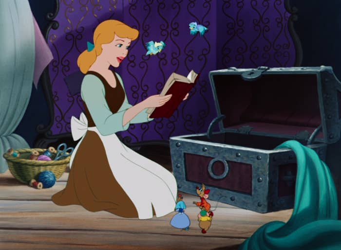 Cinderella looking at a book while her woodland friends in little hats gather around her