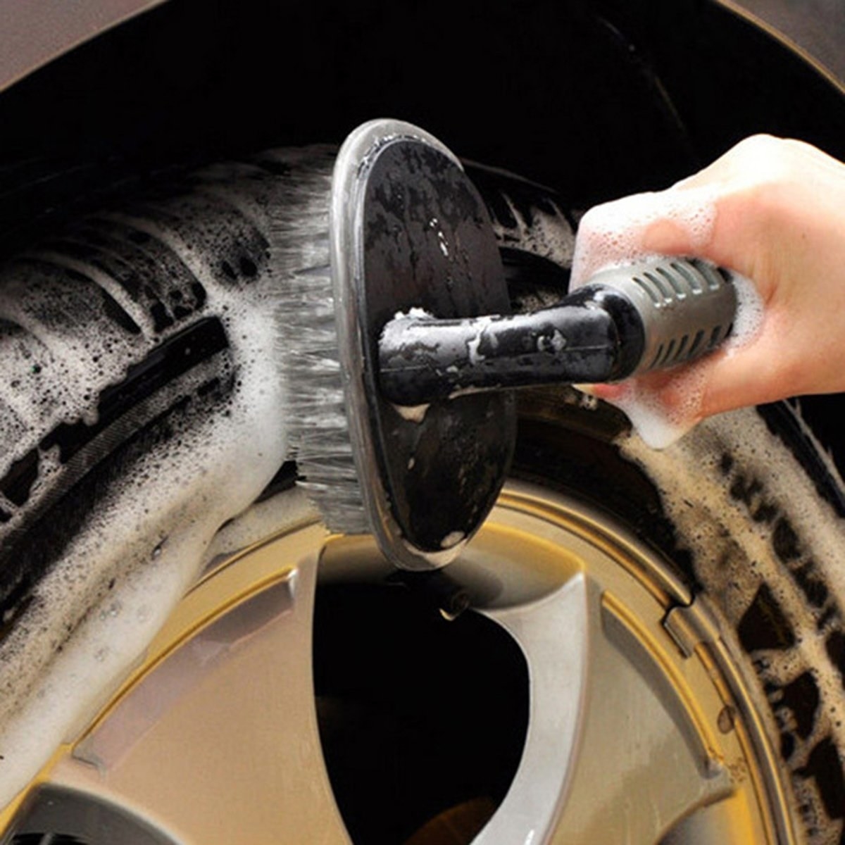 A hand cleaning a tyre with the cleaning brush.