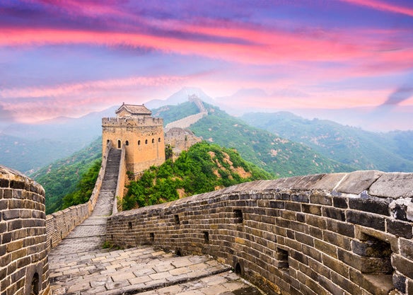 The Great Wall of China sloping over the hills with a stunning pink and purple sunset
