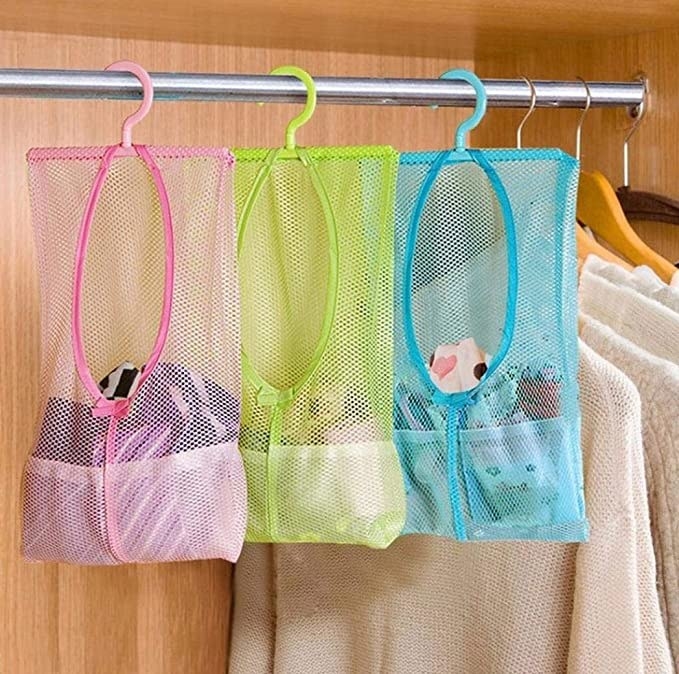 Clothes hanging in the mesh bags in the closet.