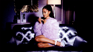 Ariana Grande in the TV show &quot;Scream Queens&quot; sitting on a couch with a big furry jacket on filing her nails