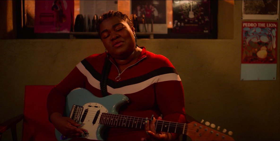 A &quot;High Fidelity&quot; still of Da&#x27;Vine Joy Randolph singing while strumming her guitar 