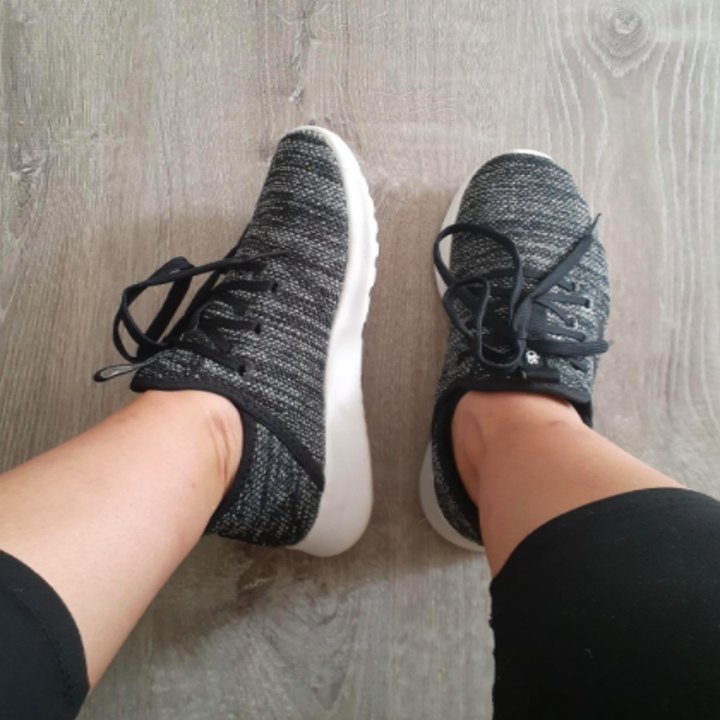 Reviewer wears same Adidas running shoes in a gray shade while placing feet on hardwood floor