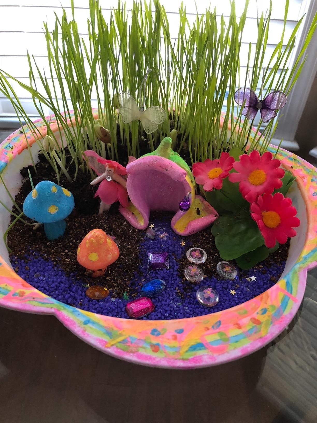 Reviewer photo of their painted garden with magical toadstools, butterflies, and a fairy