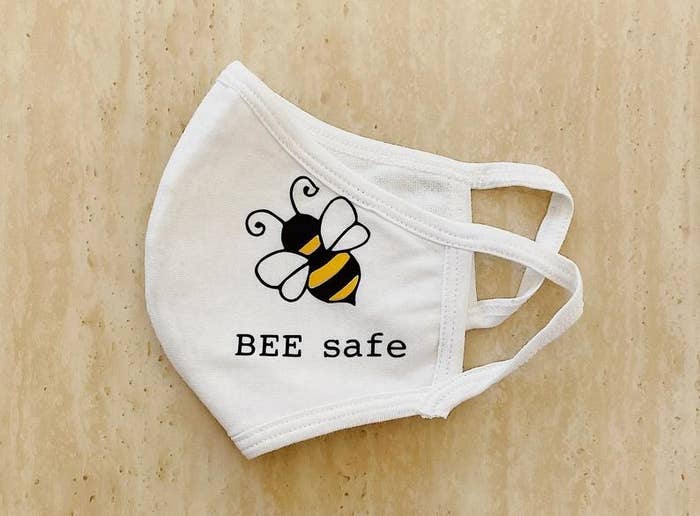 A mask with ear hooks that has a bee and says bee safe