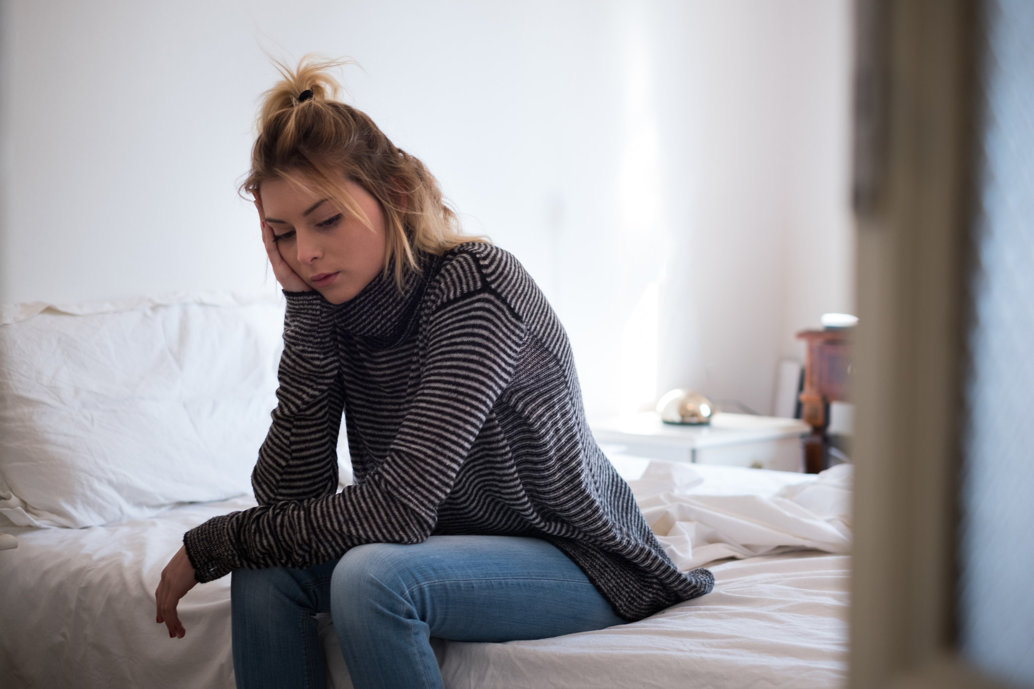 Sad young woman sitting on a bed