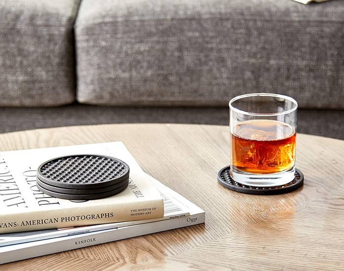 A glass of brown liquor on one of the bubble coasters on a wooden coffee table
