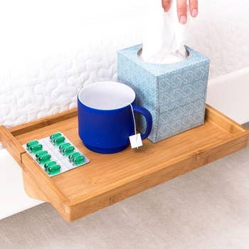 closeup of the table, showing it holding a tissue box, mug and medicine 