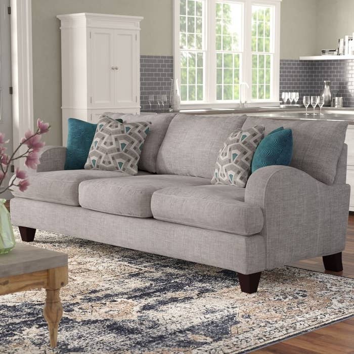 The gray fabric sofa with its teal and gray patterned throw pillows