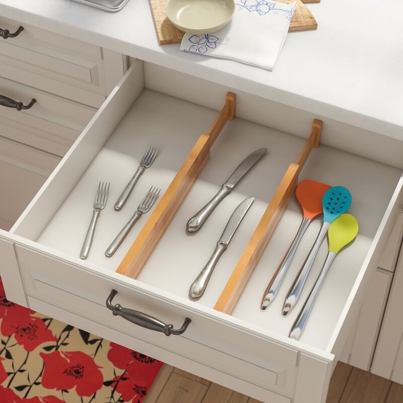 A pair of wooden, adjustable drawer dividers separating kitchen utensils and silverware