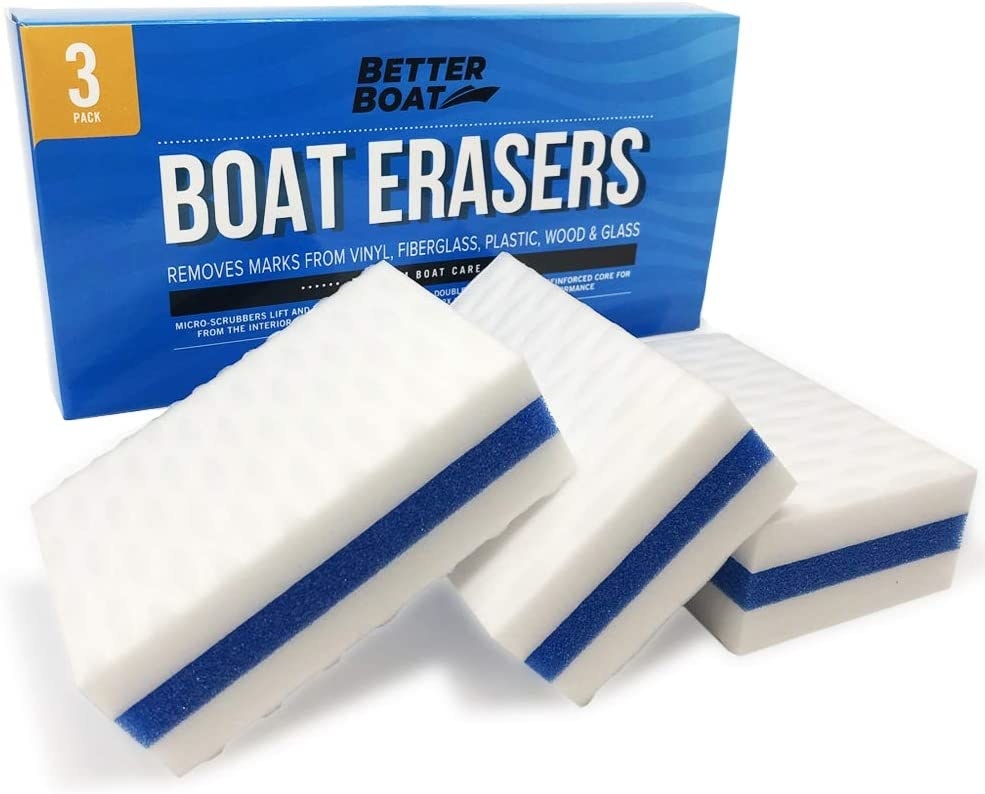 Three of the erasers in white with a blue stripe in the middle sitting in front of the box