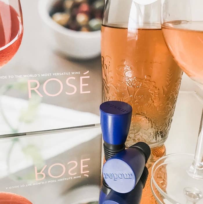 A pair of wine-saving corks next to a bottle of rosé