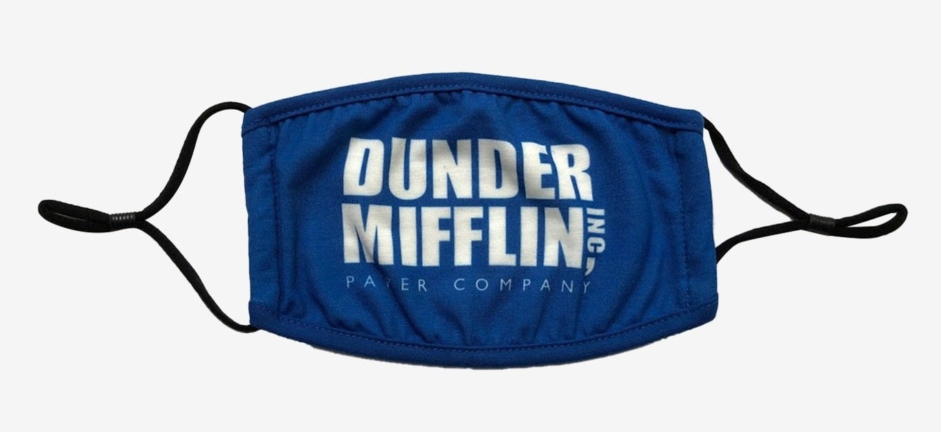 A blue nonmedical face mask with the Dunder Mifflin Inc, Paper Company logo in white on it