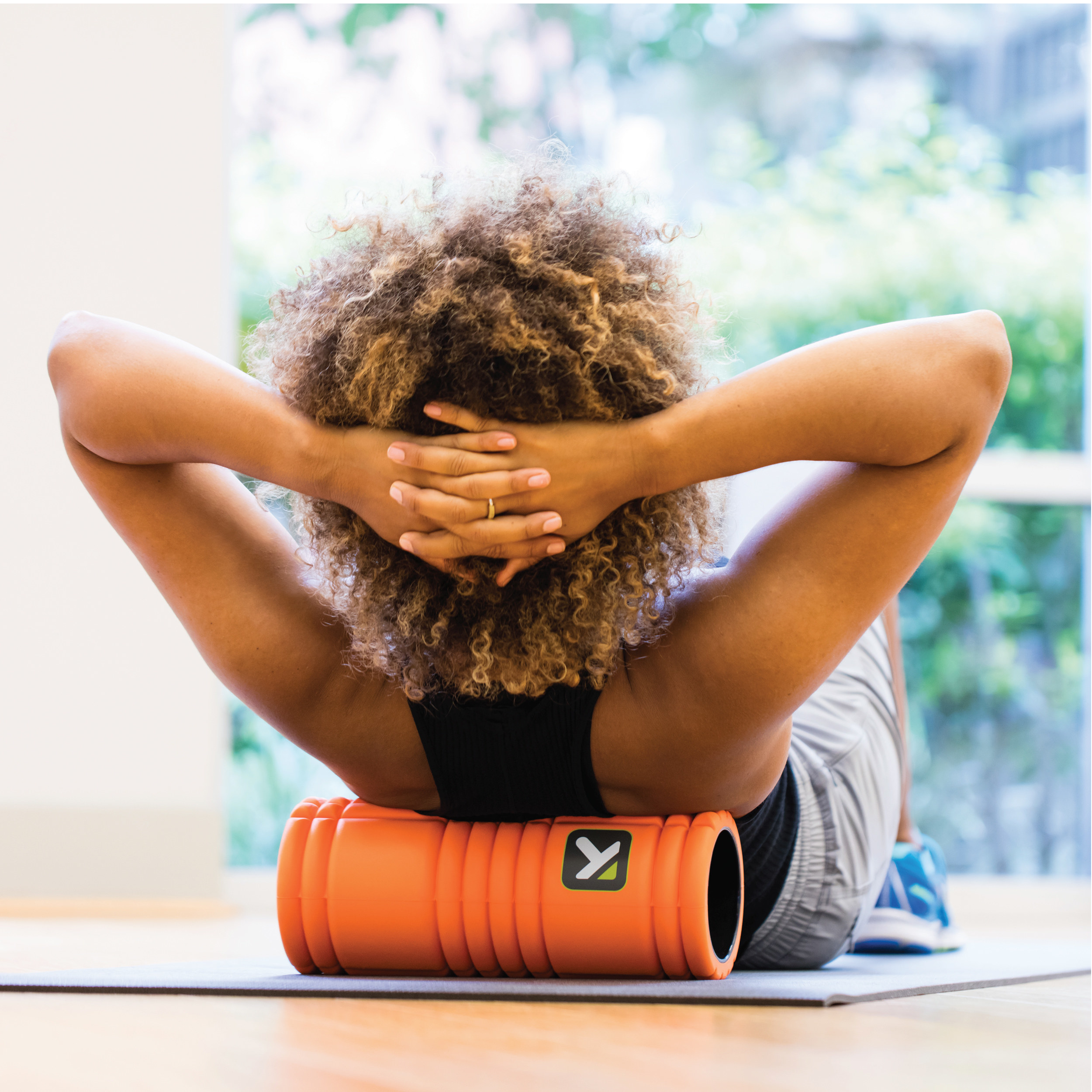 Model doing crunches while leaning back on the orange foam roller