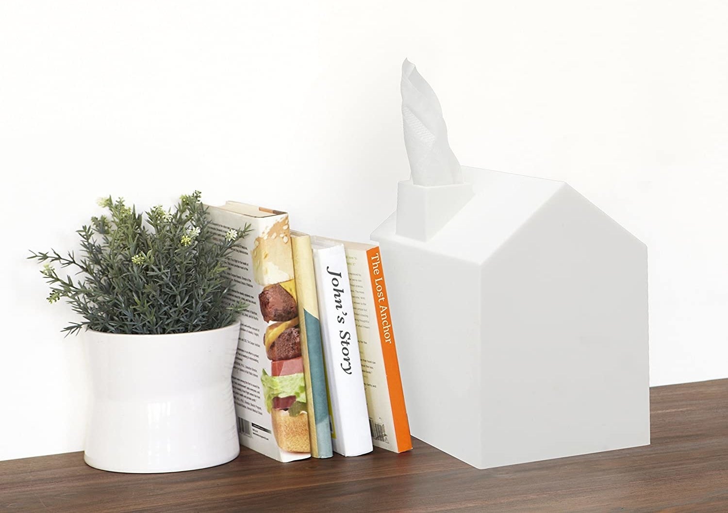 a white tissue box cover shaped like a house, the tissue looks like smoke coming out of the chimney