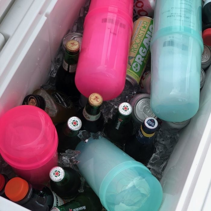 Two hot pink and two teal SubSafes in a cooler full of drinks, showing how they&#x27;re waterproof