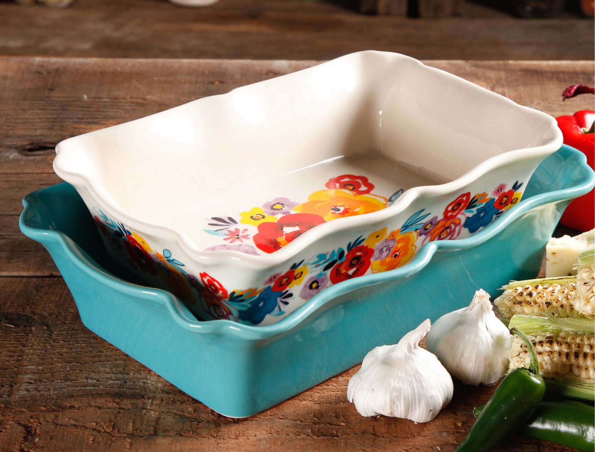 The bakeware set with one pan in a teal color, and the other is white with a colorful floral print