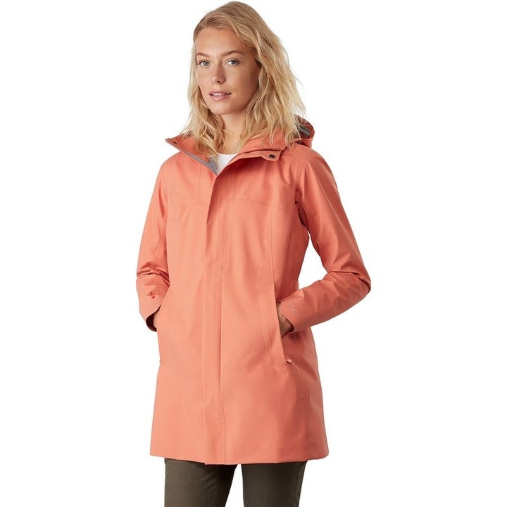 A model in a peach pink raincoat with a hood that falls at the upper thigh 