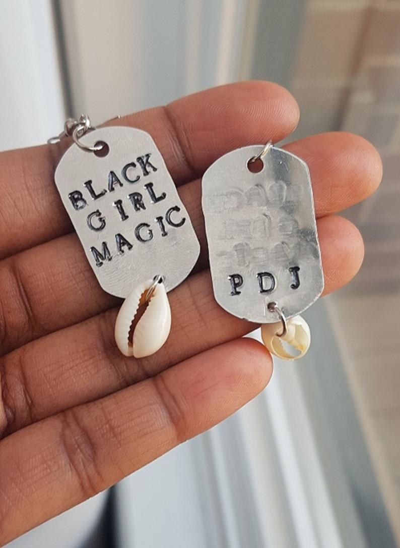 One earring says black girl magic and the other has the letters P D J