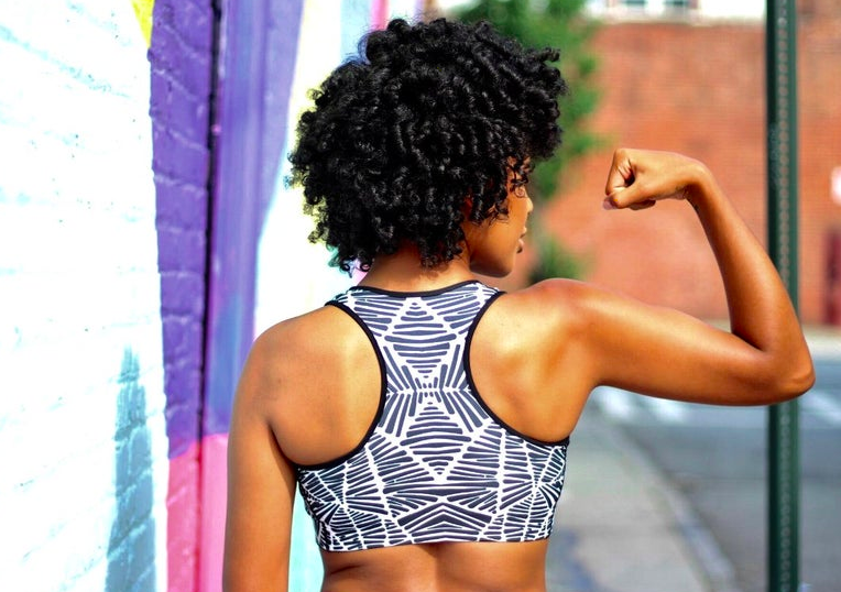 Model wears black-and-white patterned sports bra while flexing their arm 