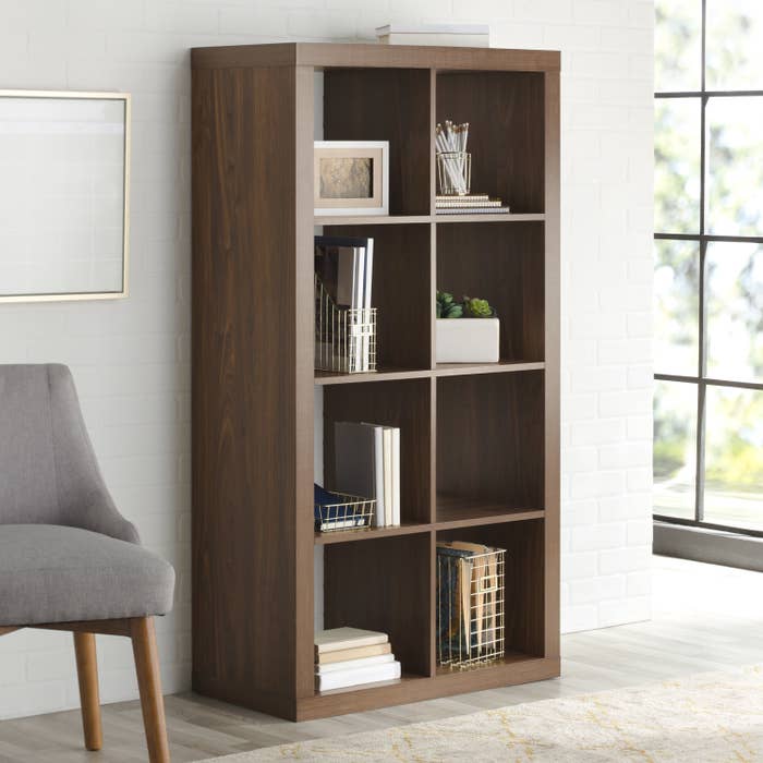 A tall shelving unit in brown with eight square sections