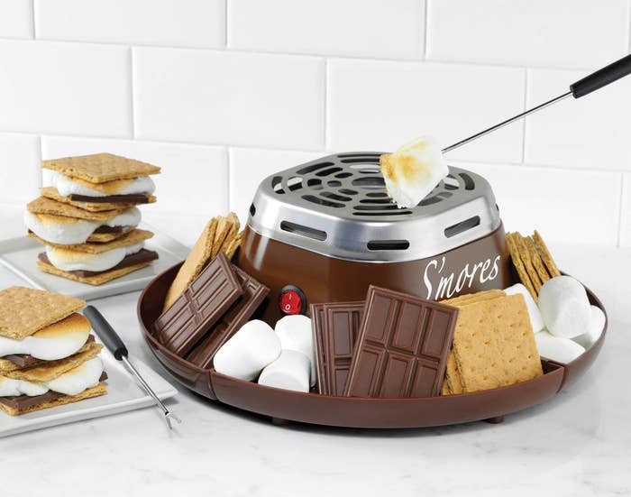 The s&#x27;mores maker, with a tray for the ingredients and a little stovetop in the middle to roast the marshmallows