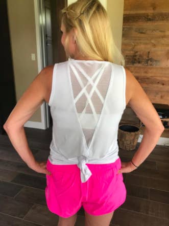 Reviewer wears white tie-back tank with pink running shorts