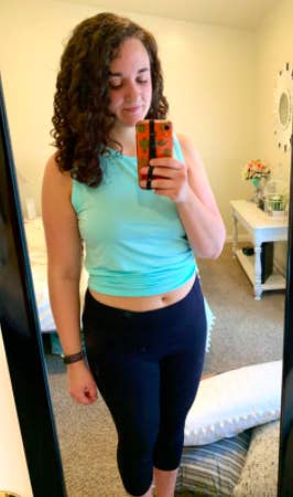 Reviewer wears same style tank in a light blue shade with black workout capris

