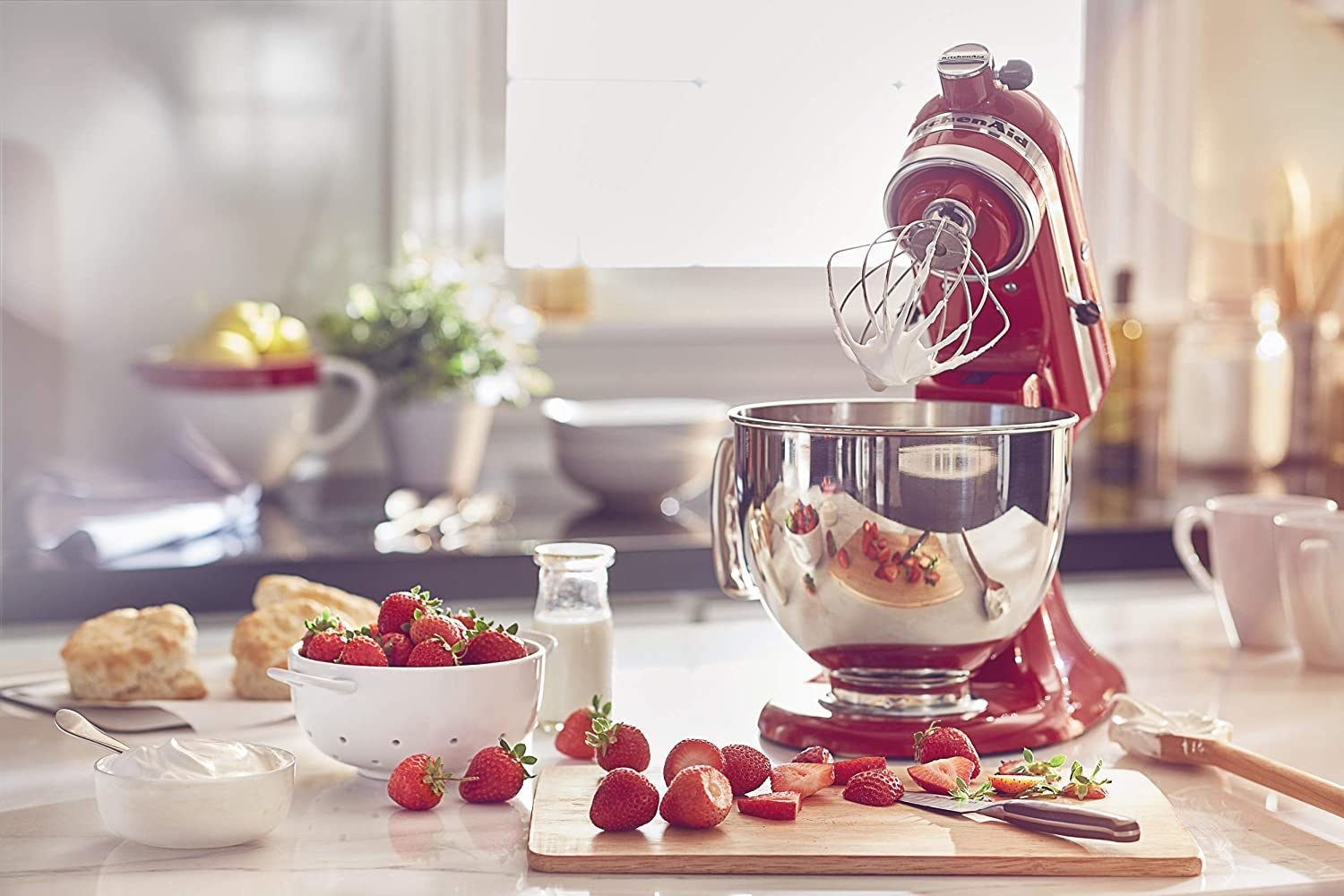 A stand mixer with the head in the upright position surrounded by berries and cream