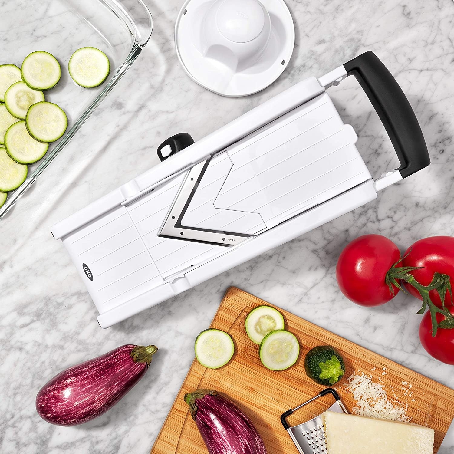 A mandolin slicer on a table surrounded be vegetables