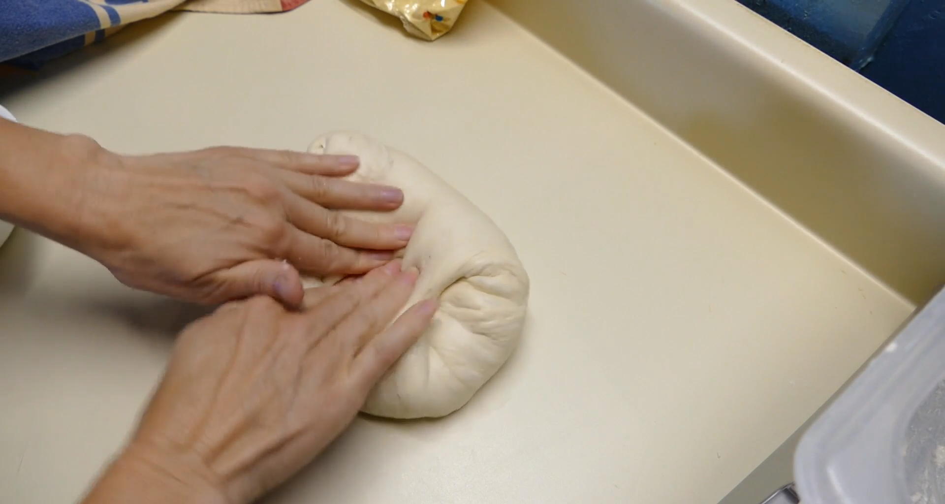 A person kneading bread dough on a counter top