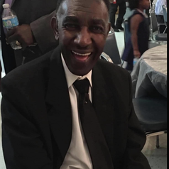 John Lewis is seen smiling and wearing a black suit amid a crowd.