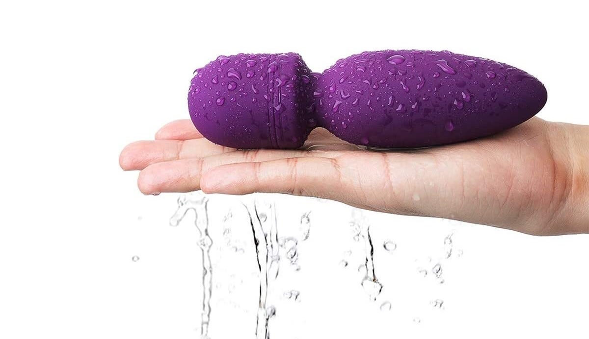 A wand vibrator that&#x27;s slightly damp lies in someone&#x27;s hand