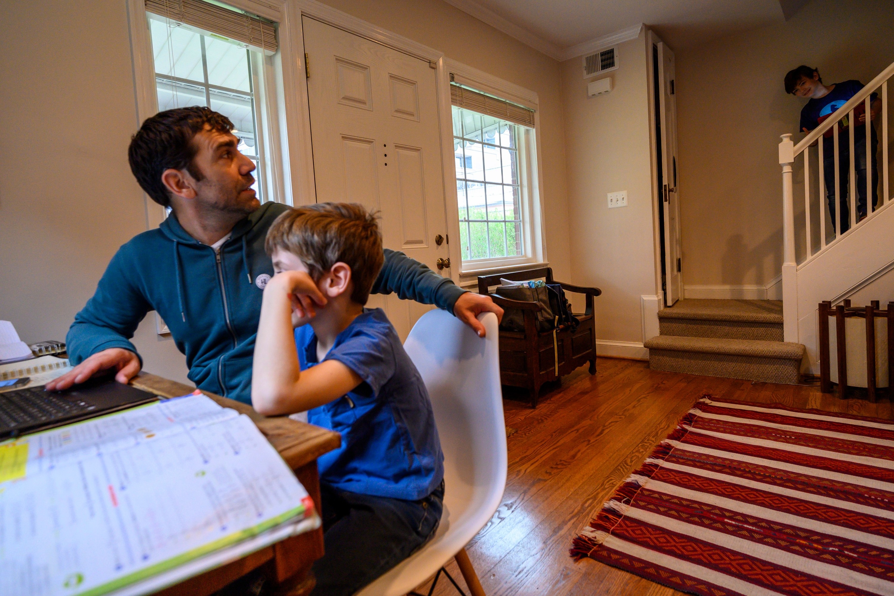 A dad homeschooling his young son.