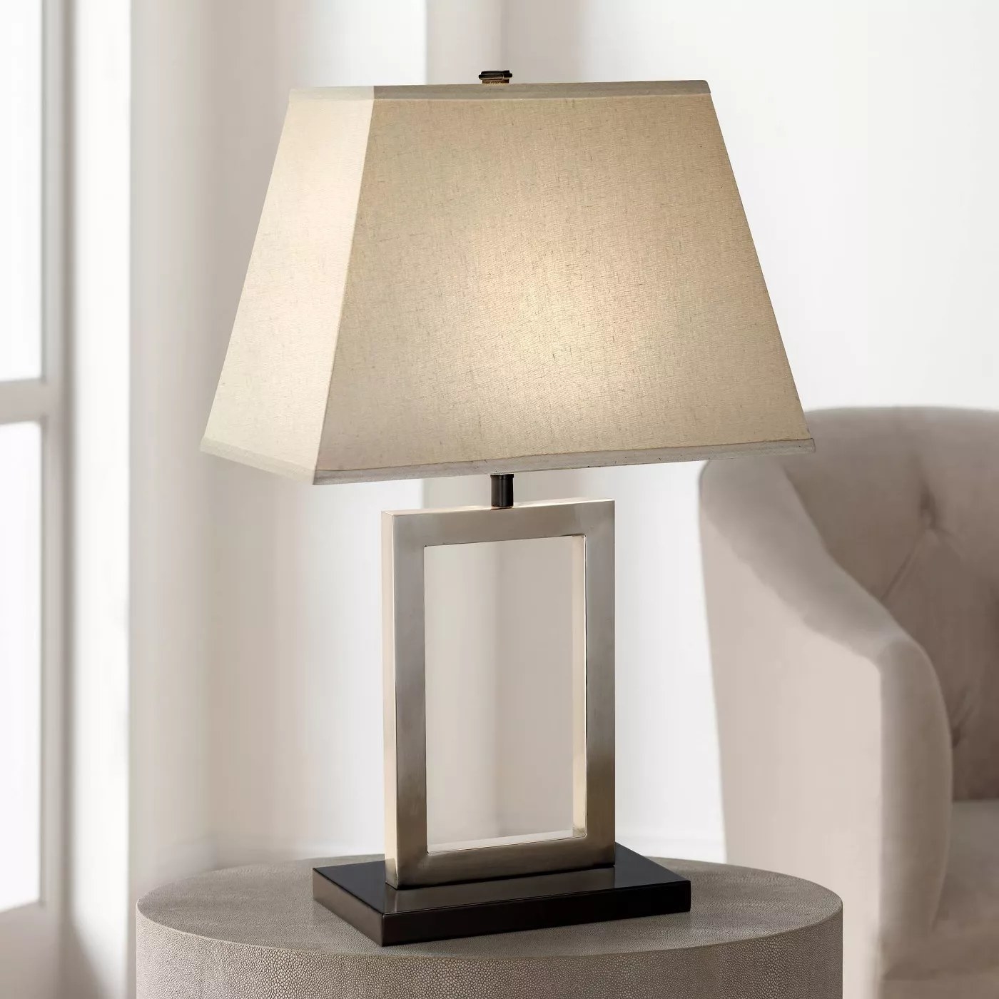 A table lamp with a rectangular base and a linen shade