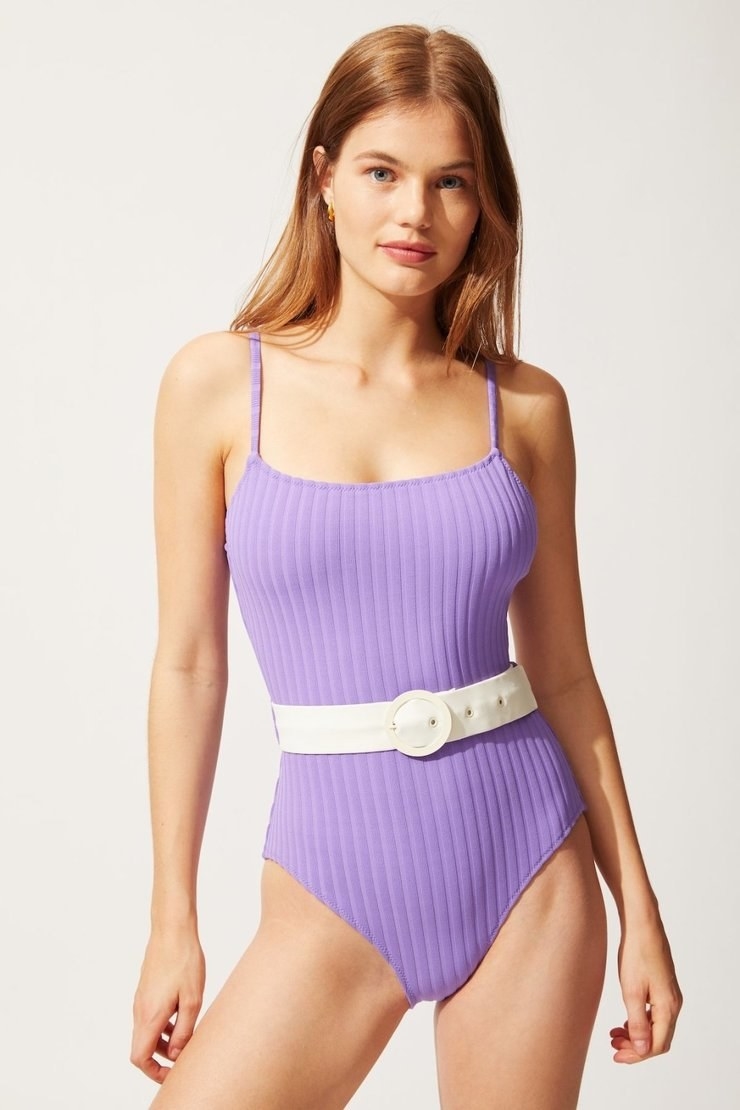 model wearing purple swimsuit with white belt