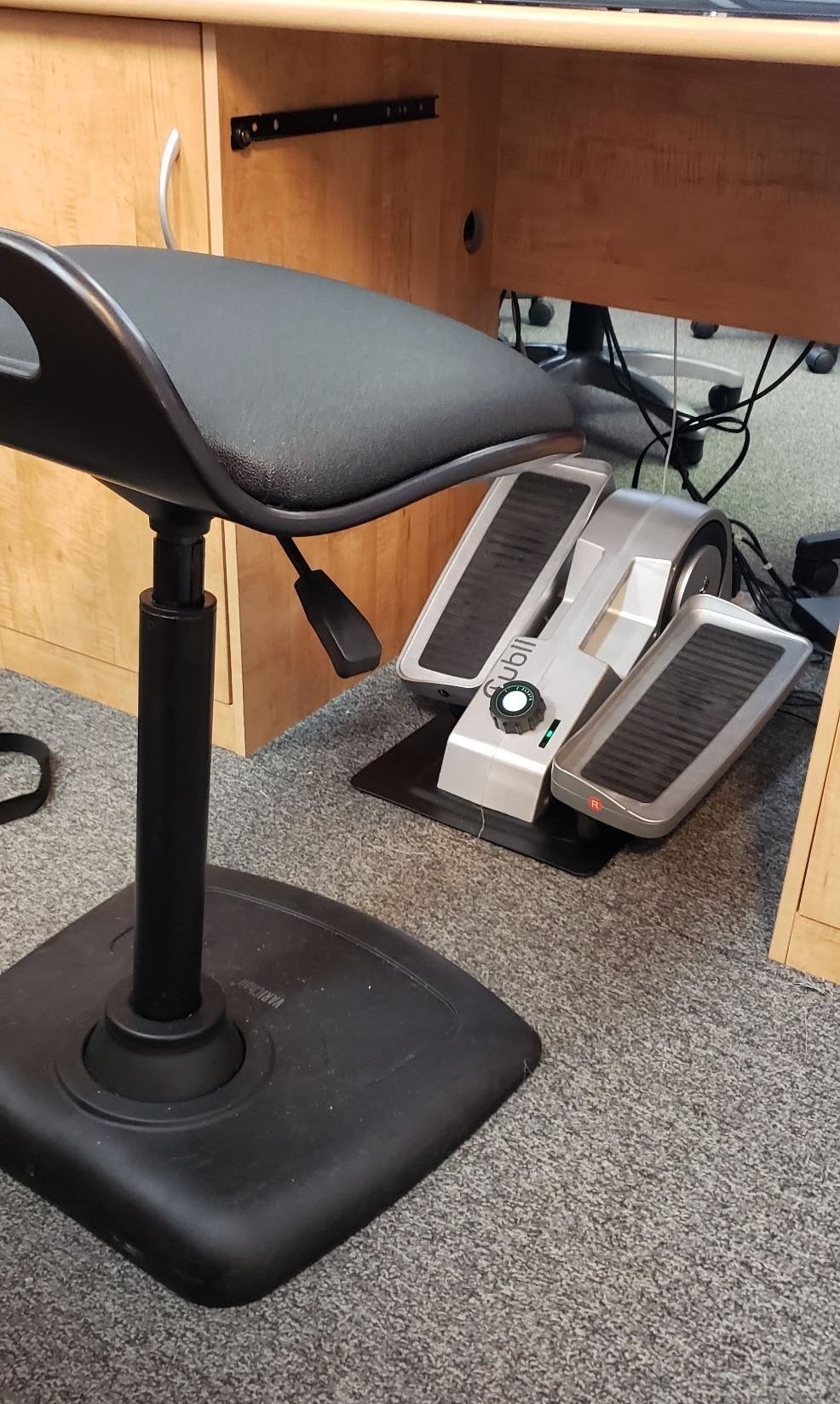 Reviewer pic of the small elliptical under a desk with a chair in front of it