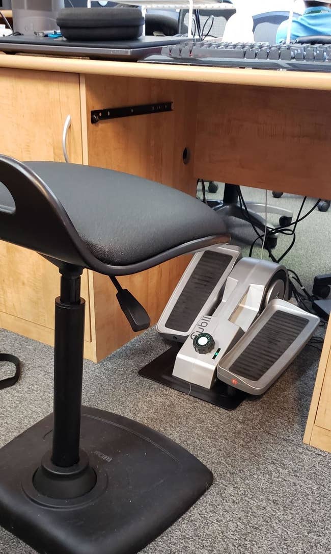 Reviewer pic of the small elliptical under a desk with a chair in front of it