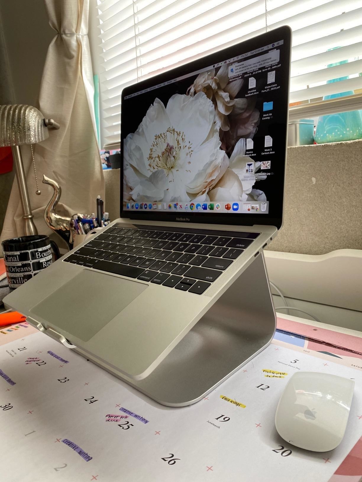 Reviewer pic of the silver laptop stand on a desk with a laptop raised on it