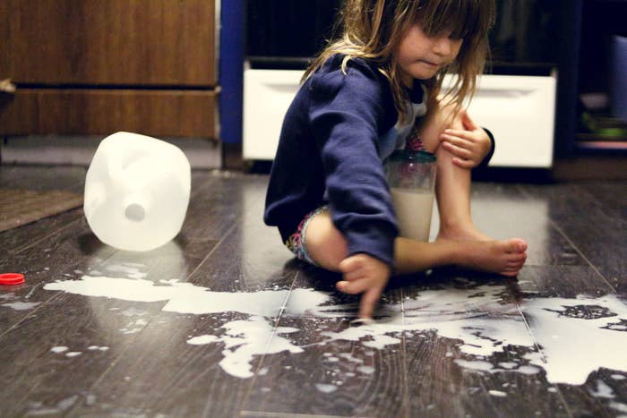 Toddler playing in spilled milk on the kitchen floor