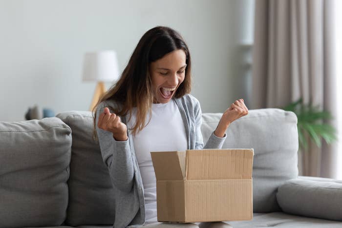 Woman making excited face with open box on her lap