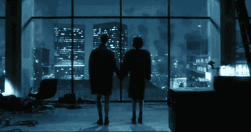Jack and Marla, holding hands, watch out of a window as buildings collapse and explode all around them.