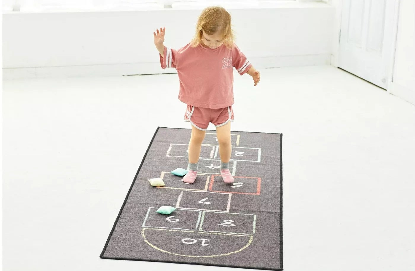 A child playing on a hopscotch rug 